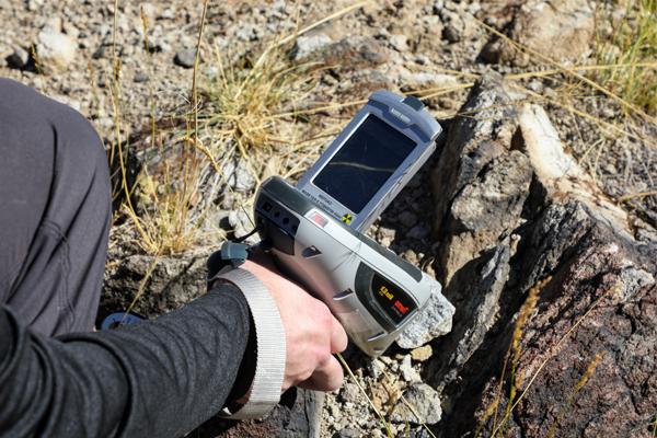 Hand holding a piece of equipment to sample rocks